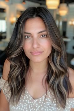 Woman with wavy brown hair and light highlights in a polka dot top, standing in a well-lit room with blurred background. Dark Dimensional Balayage, Partial Hilights On Dark Hair, Multi Dimensional Brunette Dark, Cool Tone Dimensional Brunette, Cool Toned Highlights On Dark Hair, Brunette With Slight Dimension, Brown With Lowlights, Cool Toned Dimensional Brunette, Dark Brown Hair With Subtle Highlights