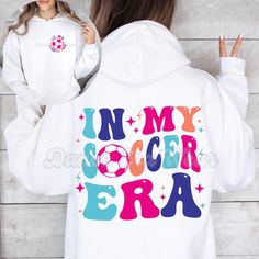 This In my Soccer Era graphic hooded sweatshirt is such a fun way to show off your love for soccer! Whether you're a soccer player looking for the perfect soccer hoodie or you're buying the perfect gift for a soccer friend , this trendy soccer hooded sweater is sure to make everyone smile. This cute Soccer sweatshirt is also available in a Comfort Colors® T shirt style. Visit our shop to see them and more Soccer sweatshirts & Soccer shirts! ▸ Gildan Brand Sweatshirt in White   ▸ Unisex Adult Sizing   ▸ 50% Cotton, 50% Polyester ▸ Medium-Heavy Fabric ▸ Rolled Sleeves in pictures is for styling purposes only   ▸ Props used In photos are NOT included with purchase SIZE ▸ Take a look at the photos to see a specific sizing chart for this sweatshirt style ▸ Please note that these sweatshirts are