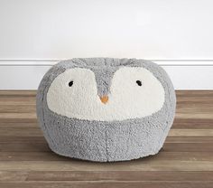 a grey and white penguin poufce sitting on top of a hard wood floor