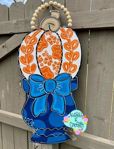 an orange and blue pumpkin shaped door hanger with a bow on it's front