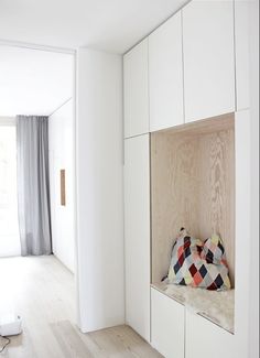 a room with white walls and wood flooring has a built in bench on the wall