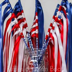 red, white and blue straws in a glass vase with streamers on the side