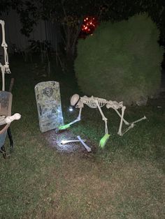 two skeleton statues in the yard at night, one is playing with a glowing light