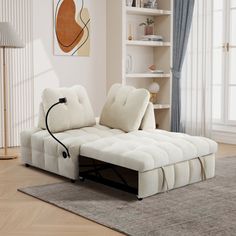 a white couch sitting on top of a wooden floor next to a book shelf filled with books