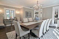 a dining room table with white chairs and a chandelier hanging from the ceiling