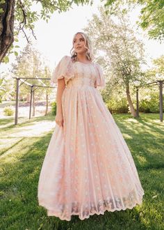 a woman wearing a pink dress standing in the grass