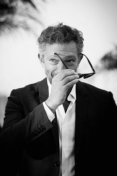 black and white photograph of a man holding glasses in front of his face