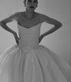 a black and white photo of a woman in a wedding dress with her hands on her hips