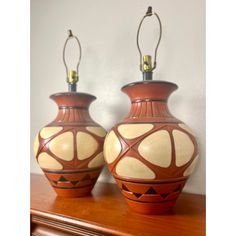 two brown and white vases sitting on top of a wooden table