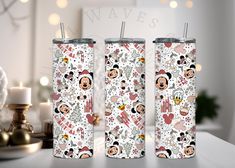 two tumbles with mickey and minnie mouse designs on them, sitting next to candles