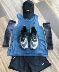 a pair of running shoes sits on the floor next to a blue shirt and black hat