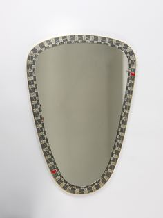 a mirror that is on the wall with a checkered border around it's edge