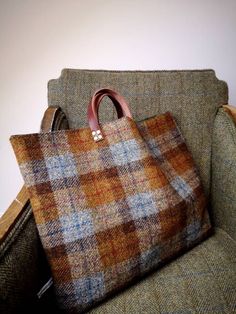 a brown and blue plaid bag sitting on top of a green couch next to a white wall