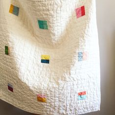 a white quilt with multicolored squares on it