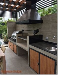 an outdoor kitchen with wood cabinets and stainless steel stove top hood over it's sink