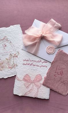 three cards with pink bows on them are laying next to an envelope and some other items