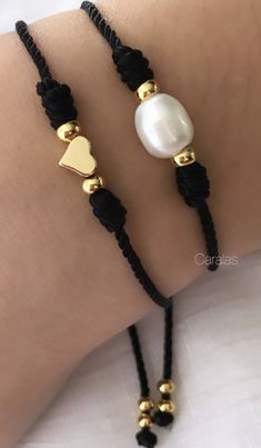 two bracelets with black and gold beads on the wrist, one has a heart charm