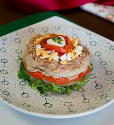 a sandwich on a plate with lettuce, tomato and other toppings sitting on a table