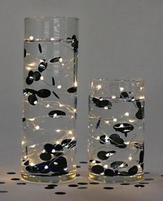 two tall glass vases filled with water and lite up leaves on the side