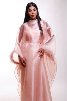 Wrap yourself in luxurious splendor with this stunning shimmer pink Organza maxi caftan dress, designed with ethereal butterfly sleeves with elegant feathers and a refined high neckline. A perfect choice for black-tie affairs, lavish resorts, wedding guests, or any occasion where timeless glamour is essential. Envision yourself gliding through a grand ballroom or strolling along an oceanfront terrace, the dress catching the light in the most alluring way. This caftan is your invitation to feel a Elegant Feathered Maxi Dress, Elegant Pink Gown With Cape Sleeves, Pink Cape Sleeves Maxi Dress For Party, Pink Party Maxi Dress With Cape Sleeves, Pink Maxi Dress With Cape Sleeves For Party, Pink Floor-length Party Abaya, Luxury Pink Maxi Evening Dress, Elegant Long Sleeve Pink Kaftan, Elegant Evening Abaya With Cape Sleeves