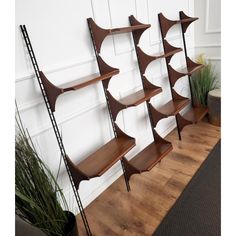 a set of three wooden shelves sitting on top of a hard wood floor next to a potted plant