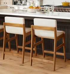 two white chairs sitting in front of a kitchen island with an oven and counter top