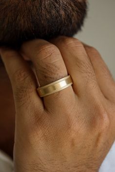 a man wearing a gold wedding band on his finger