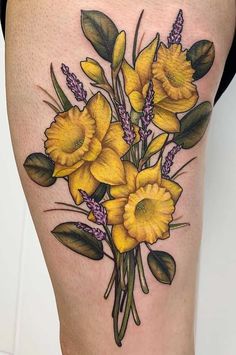 a woman's thigh with yellow flowers and green leaves on the side, in front of her