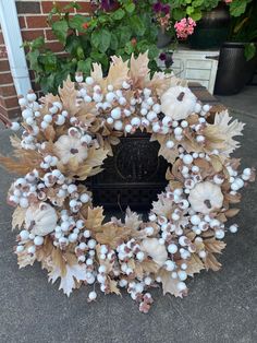 a wreath with white flowers and leaves is sitting on the ground in front of a brick building