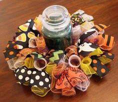 a halloween wreath made out of fabric and ribbon with a jar on the table next to it