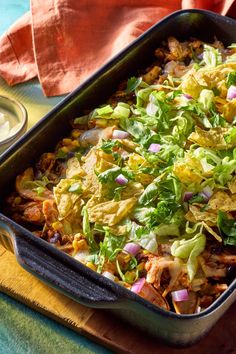 a casserole dish with lettuce, onions and other vegetables in it