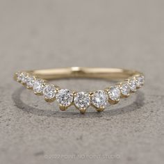 a yellow gold ring with five diamonds on the top and bottom, sitting on concrete