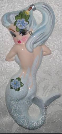 a ceramic mermaid figurine with blue hair and flowers on it's tail