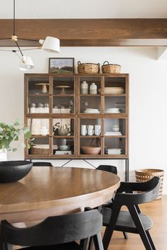 a dining room table with chairs and shelves in the background