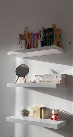 two white shelves with books and other items on them