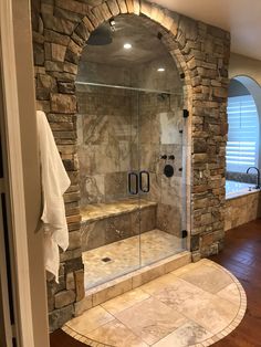 a bathroom with stone walls and a walk in shower next to a wooden flooring area