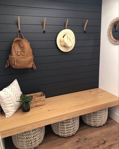 a wooden bench with two baskets and a hat on it next to a wall mounted coat rack