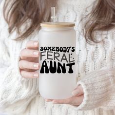 someone holding a white coffee mug with the words somebody's ferall aunt on it