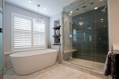 a white bath tub sitting next to a walk in shower under a chandelier