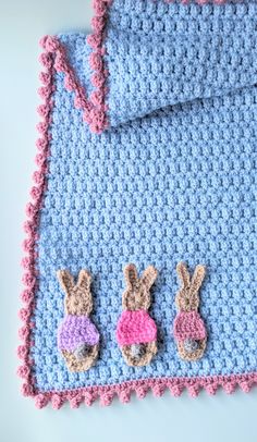 crocheted baby blanket with bunny ears on it and two little stuffed bunnies