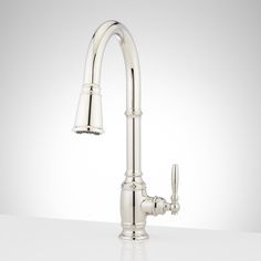 a white kitchen sink faucet with chrome handles