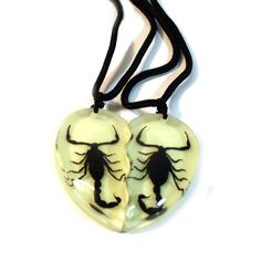 two heart shaped glass pendants with black and white designs on them, hanging from a black cord