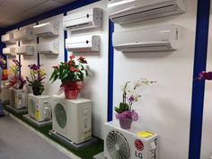 several air conditioners are lined up against the wall with flowers in vases on them