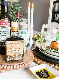 bottles of alcohol sitting on top of a wooden table next to plates with food and candles