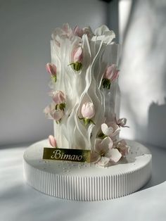 a white cake with pink flowers on top and a name tag that says binas