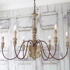 a chandelier hanging from the ceiling in front of wooden paneled walls and doors