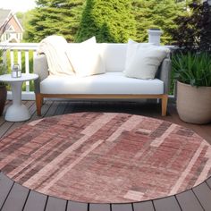 a large rug on a wooden deck next to a couch and table with potted plants