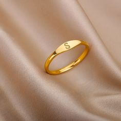 Our Initial Ring is a beautiful and elegant piece of minimalist jewelry, perfect for any occasion.  This tiny ring, available in either gold or silver, is the perfect gift for the special woman in your life. With a single initial featured prominently on the front, this ring is a subtle and sophisticated way to personalize your style.  Whether you are looking for a monogrammed piece to add to your collection or a simple, yet chic accessory to complete your outfit, this Initial Ring is sure to imp Ring Designs Simple Gold, Gold Ring With Initials, Gold Rings For Woman, Gold Simple Ring For Women, S Letter Rings For Women, Initial Rings For Ladies, Gold Minimalist Personalized Initial Ring, Personalized Gold Initial Ring Minimalist Style, Simple Personalized Gold Stackable Rings