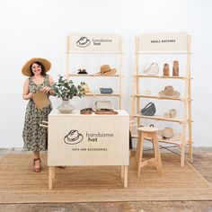 a woman standing next to a display case with hats on it's shelves and holding a piece of paper