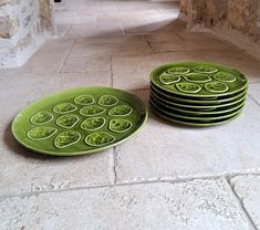 a stack of green plates sitting on top of a stone floor next to each other